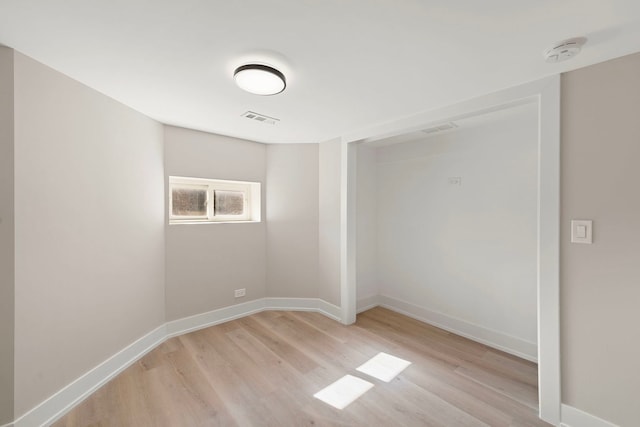 empty room featuring baseboards, visible vents, and light wood finished floors