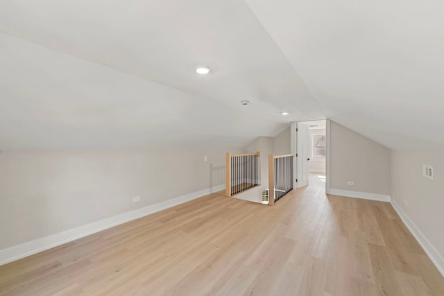 bonus room featuring lofted ceiling, light wood-style flooring, and baseboards