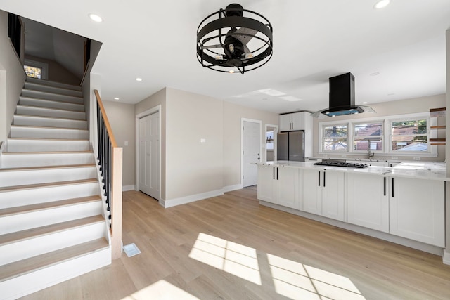 kitchen featuring light wood finished floors, appliances with stainless steel finishes, island exhaust hood, and white cabinets