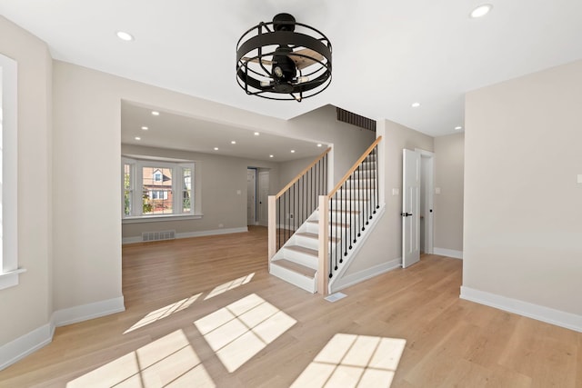 interior space with stairway, wood finished floors, visible vents, and baseboards