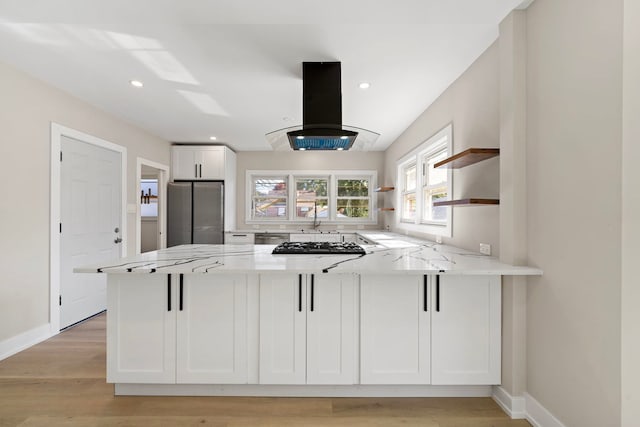 kitchen featuring white cabinets, freestanding refrigerator, a peninsula, island exhaust hood, and open shelves