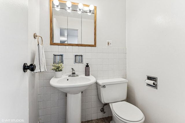 bathroom with toilet and tile walls