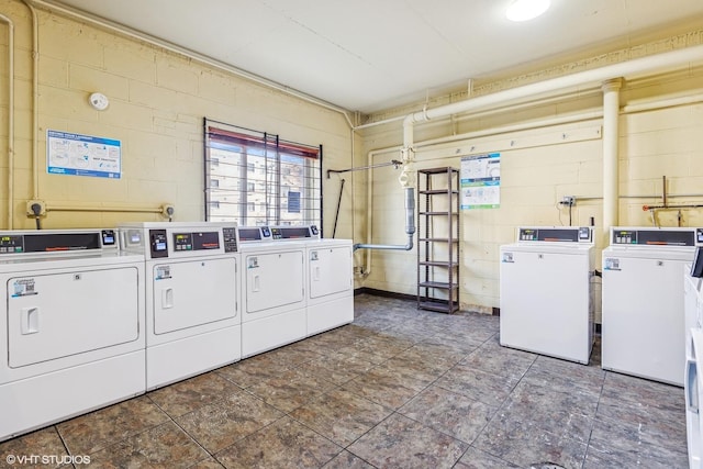 community laundry room featuring concrete block wall and washer and clothes dryer