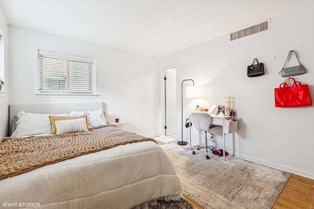 bedroom featuring wood finished floors, visible vents, and baseboards