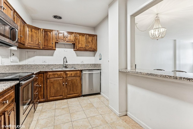 kitchen with a sink, tasteful backsplash, stainless steel appliances, light tile patterned floors, and light stone countertops