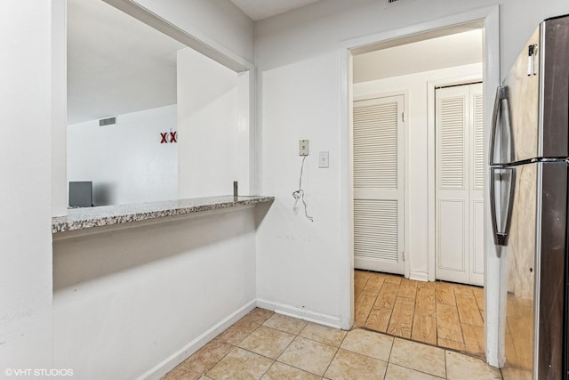 kitchen featuring light tile patterned floors, visible vents, freestanding refrigerator, and baseboards