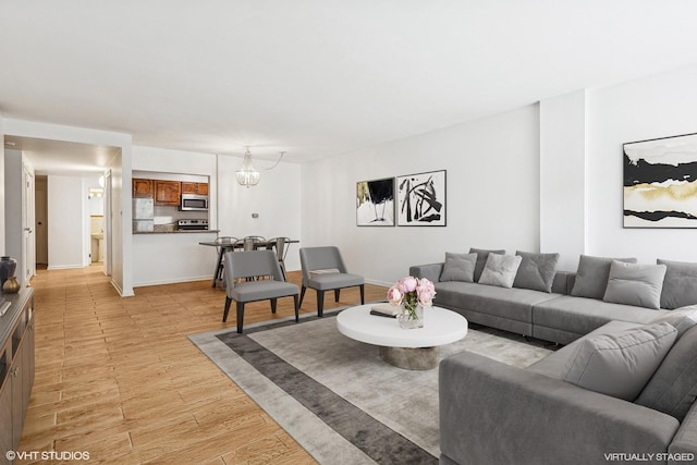 living area with baseboards, light wood-style floors, and an inviting chandelier