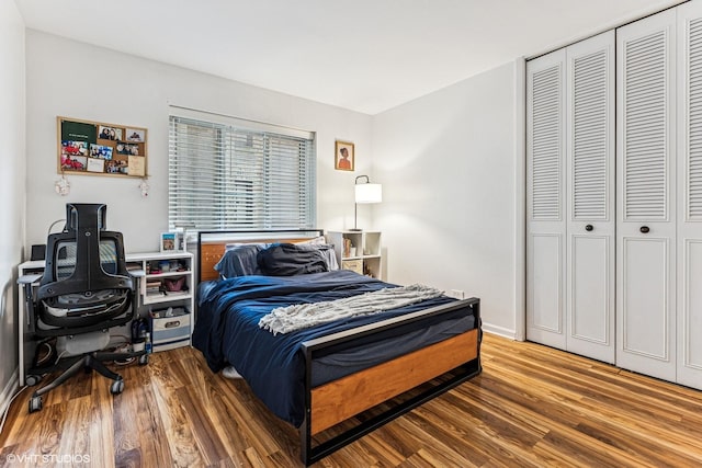 bedroom with wood finished floors, a closet, and baseboards