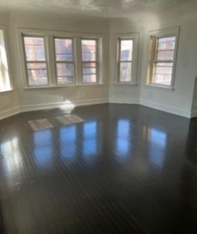 spare room with dark wood-type flooring and baseboards