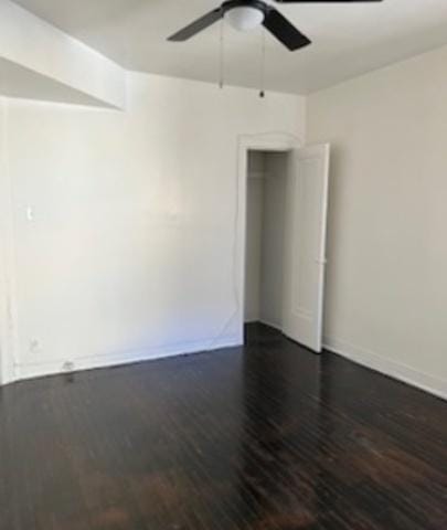 spare room featuring ceiling fan, dark wood finished floors, and baseboards