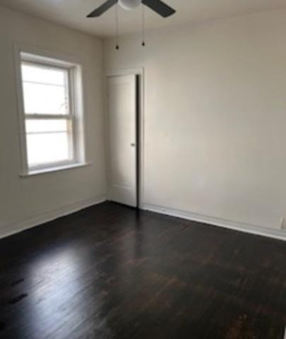 spare room featuring dark wood finished floors, a ceiling fan, and baseboards