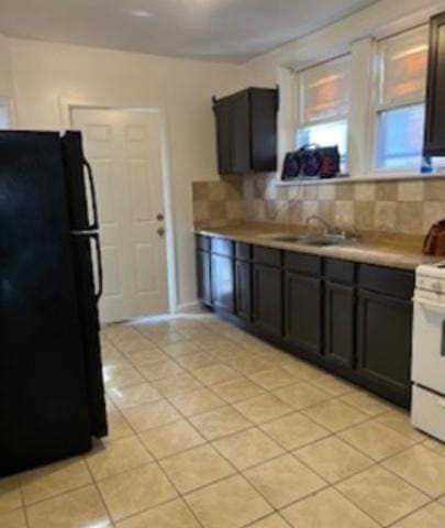 kitchen with white electric range, backsplash, a sink, and freestanding refrigerator