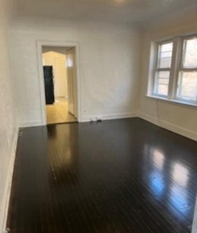 empty room with baseboards and wood finished floors