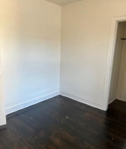 spare room with dark wood-style floors and baseboards