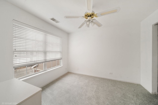 spare room with a ceiling fan, visible vents, light carpet, and baseboards