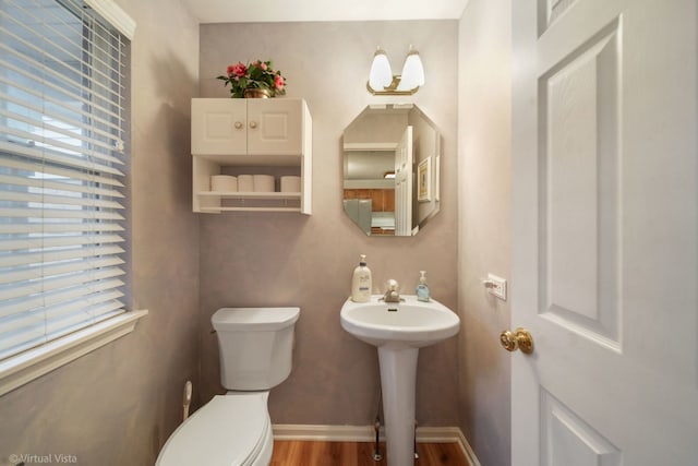 half bathroom featuring a healthy amount of sunlight, baseboards, and toilet