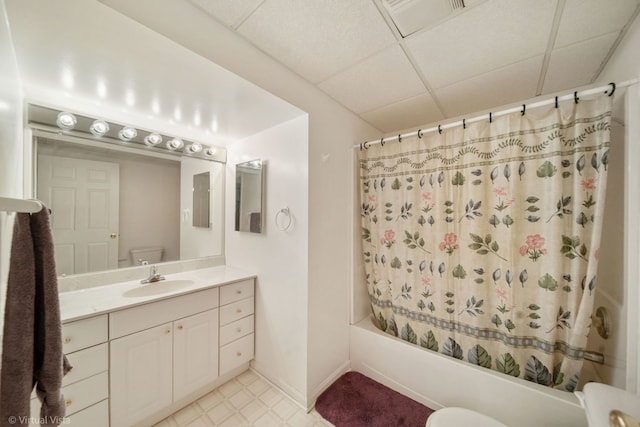 full bath with a paneled ceiling, shower / bathtub combination with curtain, toilet, vanity, and tile patterned floors