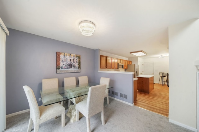 dining space with light colored carpet, visible vents, and baseboards