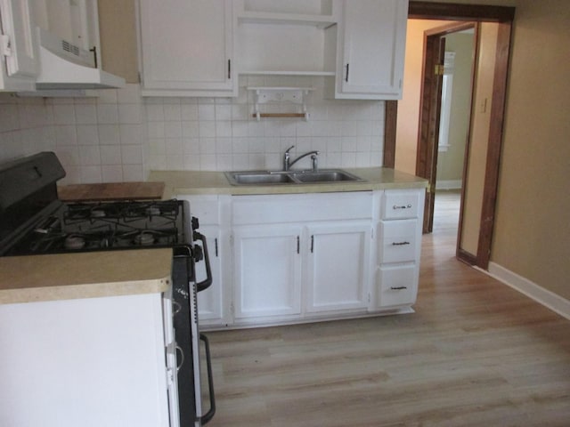 kitchen featuring range with gas stovetop, white cabinetry, a sink, and under cabinet range hood