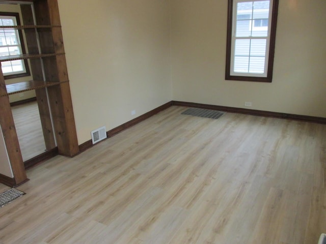 unfurnished room with wood finished floors, visible vents, and baseboards