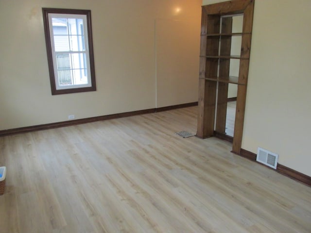 unfurnished room featuring visible vents, baseboards, and wood finished floors