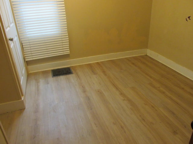 empty room with visible vents, baseboards, and wood finished floors