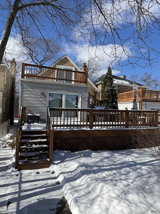 snow covered property featuring a wooden deck and a balcony