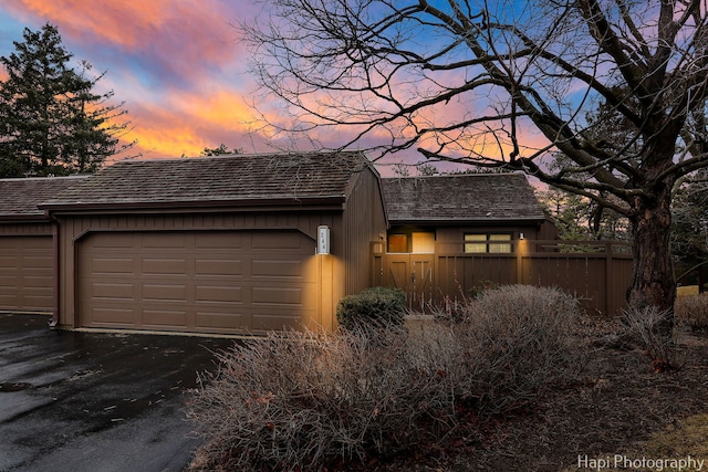 exterior space with driveway, an attached garage, and fence