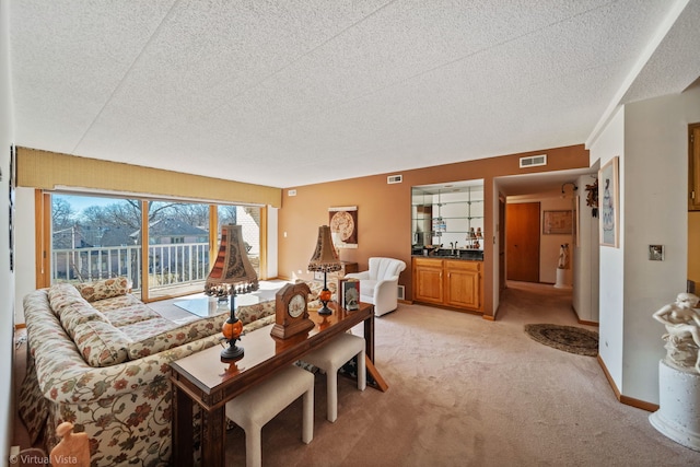 living area featuring baseboards, light colored carpet, visible vents, and a textured ceiling