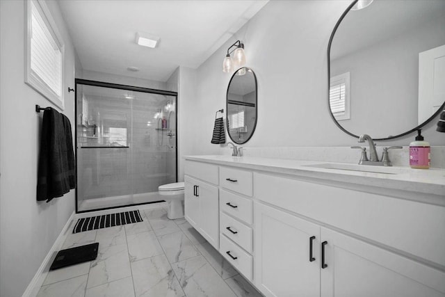 bathroom with double vanity, a sink, a shower stall, toilet, and marble finish floor