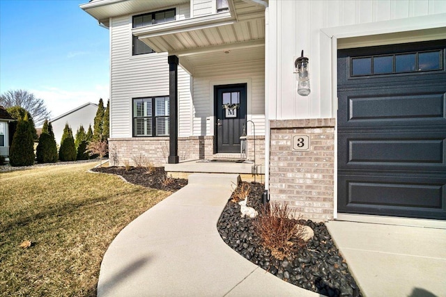 doorway to property featuring brick siding, a yard, board and batten siding, and a garage