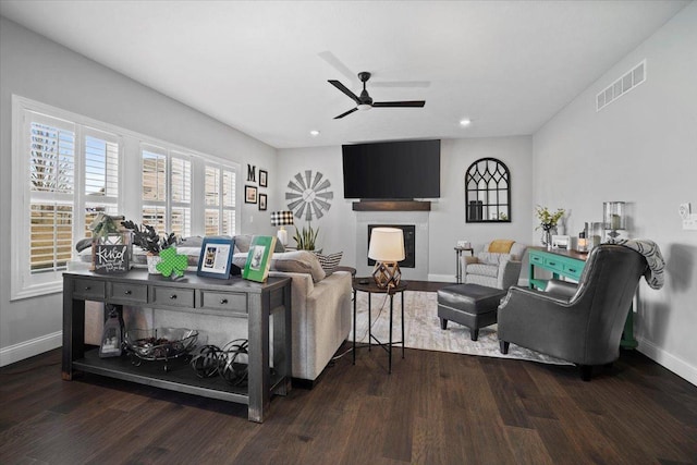 living area with visible vents, a fireplace, baseboards, and wood finished floors