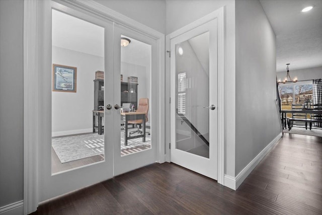 hall featuring french doors, baseboards, a notable chandelier, and dark wood-style flooring