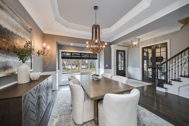 dining space featuring a tray ceiling, wood finished floors, a wainscoted wall, and a chandelier