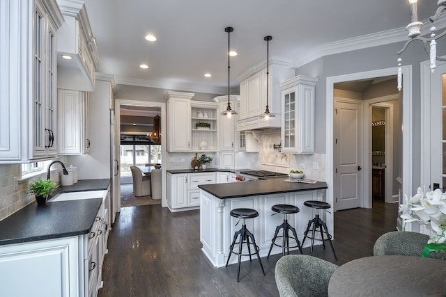 kitchen with dark countertops, white cabinetry, a kitchen bar, and open shelves