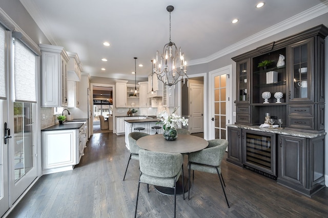 dining area with beverage cooler, dark wood finished floors, recessed lighting, crown molding, and a notable chandelier