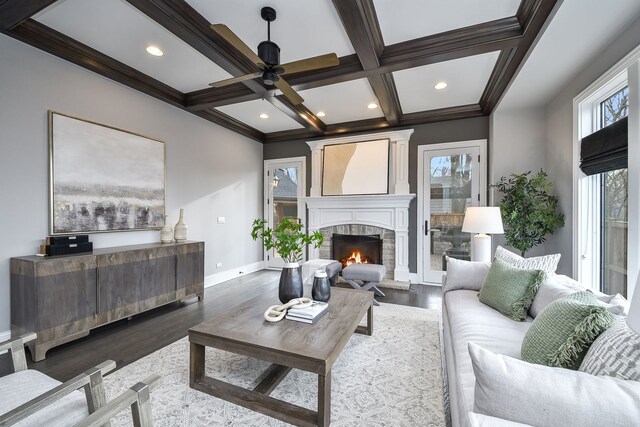 living area featuring wood finished floors, baseboards, coffered ceiling, beam ceiling, and ceiling fan