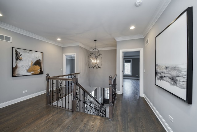 hall with visible vents, baseboards, ornamental molding, an upstairs landing, and wood finished floors