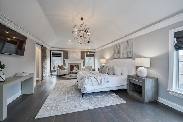 bedroom with ornamental molding, a warm lit fireplace, dark wood-style floors, a barn door, and baseboards