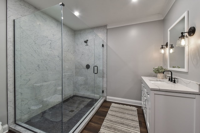 full bath featuring vanity, wood finished floors, baseboards, a stall shower, and crown molding