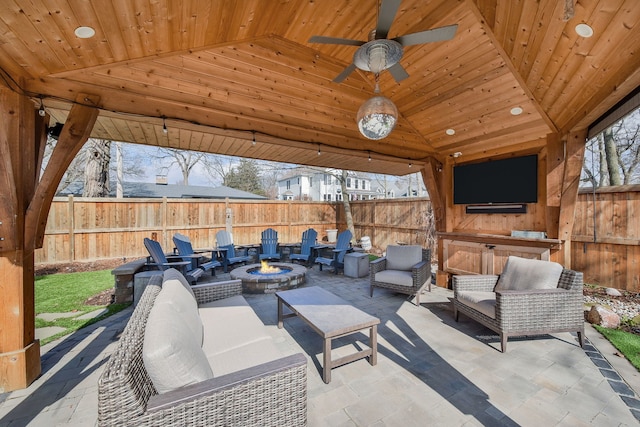 view of patio featuring an outdoor living space with a fire pit, a gazebo, fence, and a ceiling fan