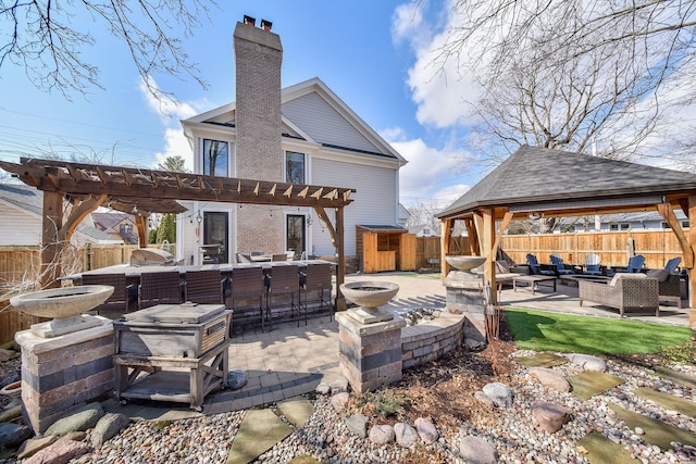 back of property featuring a fenced backyard, a pergola, a chimney, an outdoor living space with a fire pit, and a patio area