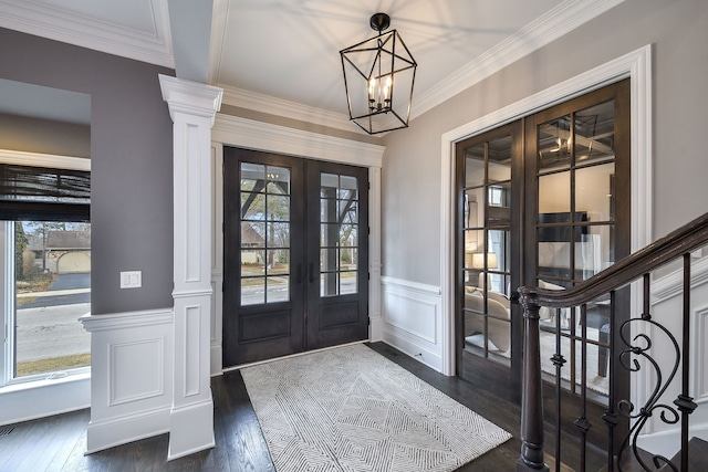 entryway featuring ornate columns, dark wood finished floors, french doors, wainscoting, and a chandelier