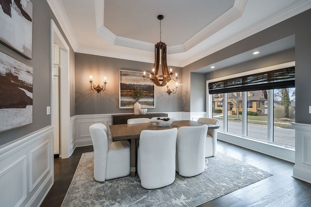 dining area with an inviting chandelier, a tray ceiling, dark wood-style floors, and wainscoting