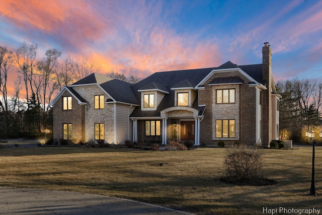 view of front of property featuring stone siding, a chimney, and a front lawn