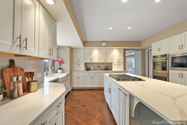 kitchen with white cabinetry, light stone countertops, backsplash, and stainless steel appliances