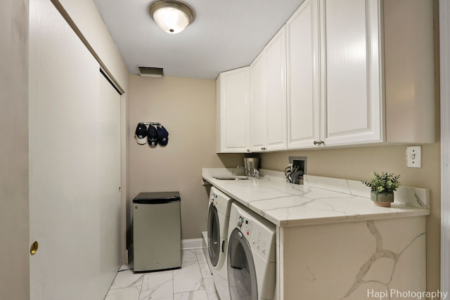 clothes washing area featuring baseboards, cabinet space, a sink, washing machine and dryer, and marble finish floor