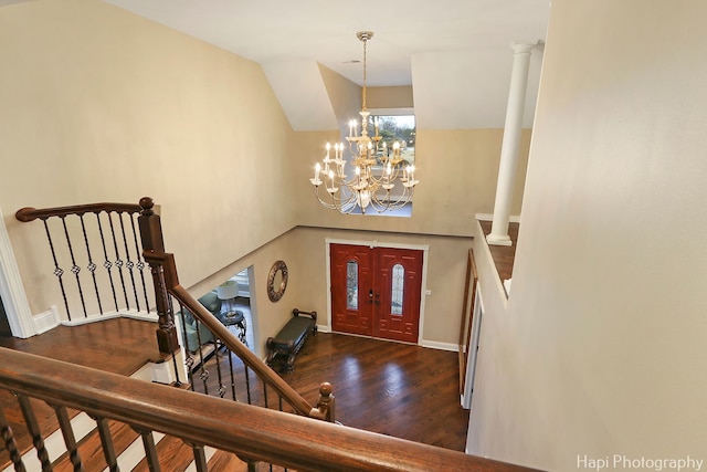 foyer entrance featuring baseboards, a chandelier, decorative columns, wood finished floors, and high vaulted ceiling