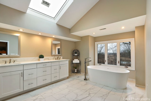 bathroom with visible vents, double vanity, a freestanding bath, a sink, and marble finish floor