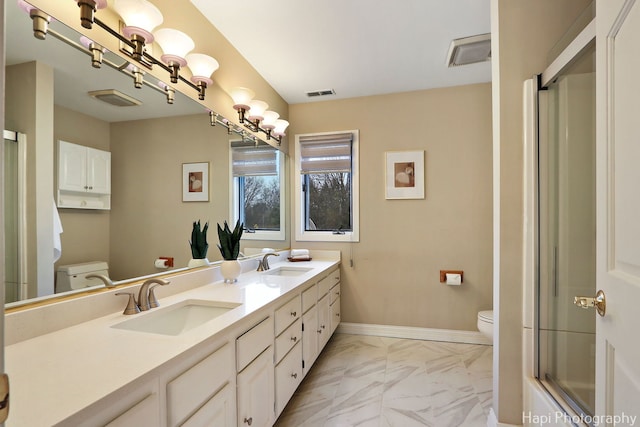 bathroom featuring a shower with shower door, toilet, baseboards, and a sink